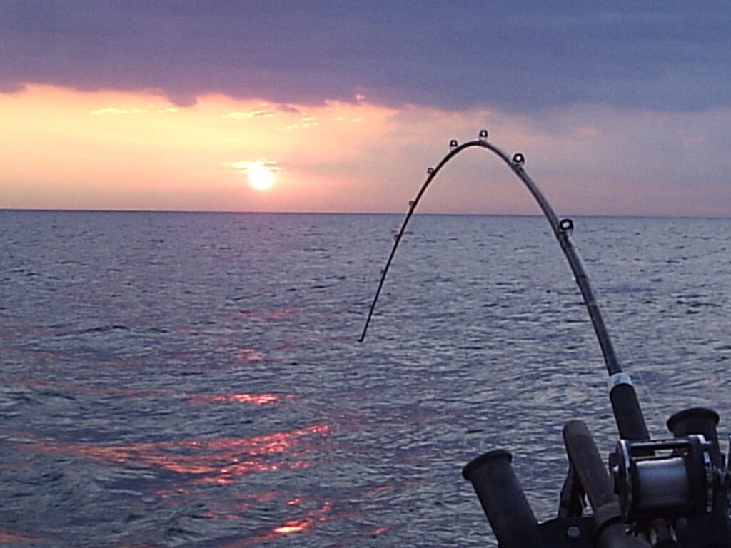 sunset on ocean with a fishing rod and reel